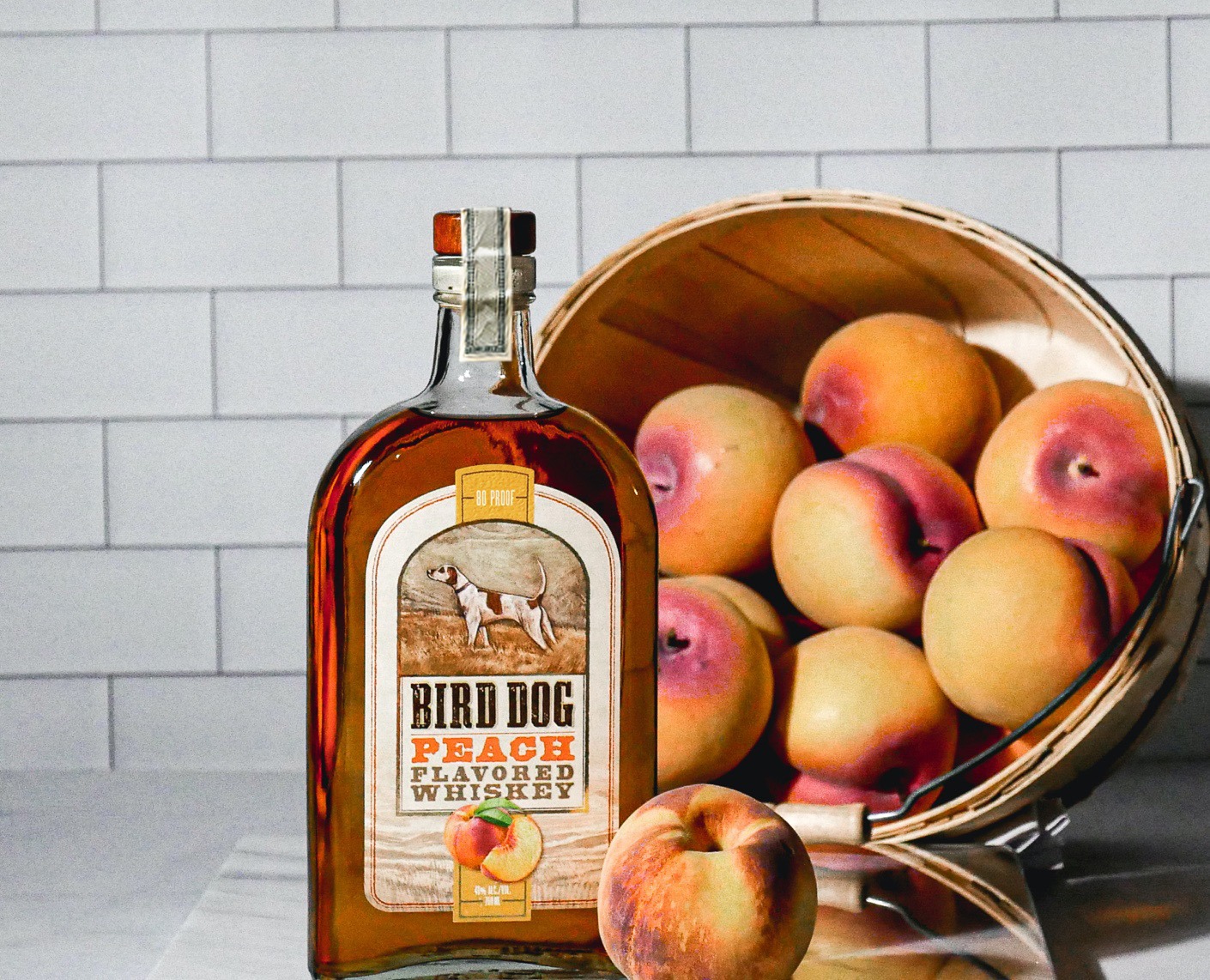 Bottle of Bird Dog Peach Whiskey Sitting Next to Peaches