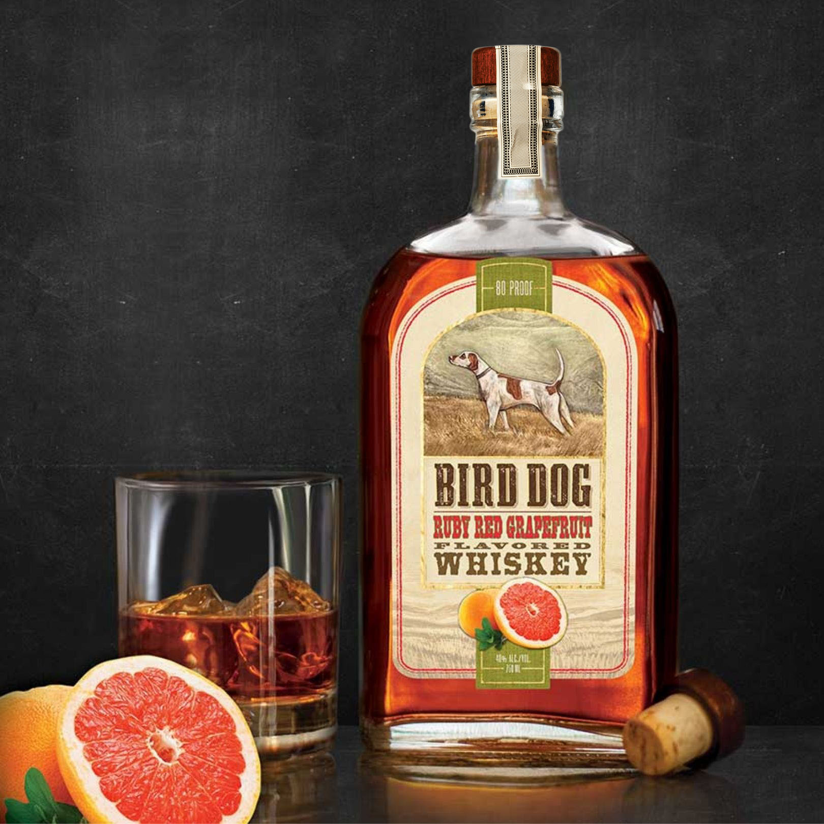 Bottle of Bird Dog Grapefruit Whiskey Sitting Next to a Cocktail